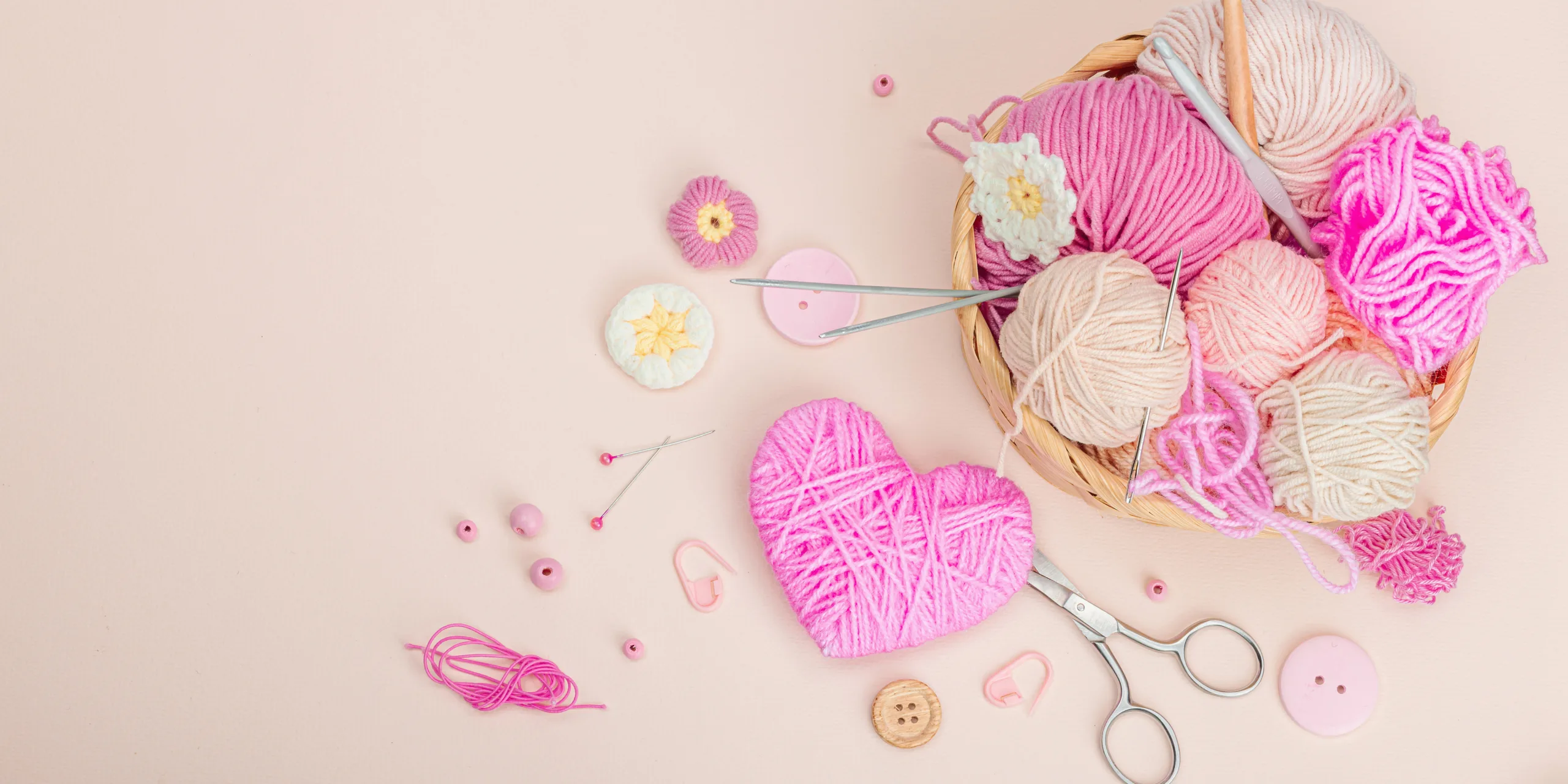 Handmade spring decor concept. Creative crocheting, traditional flowers and thread pink heart. Festive greeting card, gentle pastel apricot background, banner format